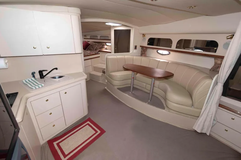 Slide: The Image of 1999 Cruisers Yachts 3575 Express interior with kitchenette, dining area, and cozy seating. - 10