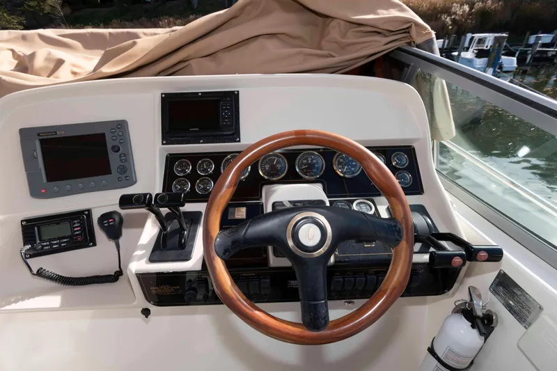 Slide: The Image of 1999 Cruisers Yachts 3575 Express helm with wooden steering wheel and navigation instruments. - 7