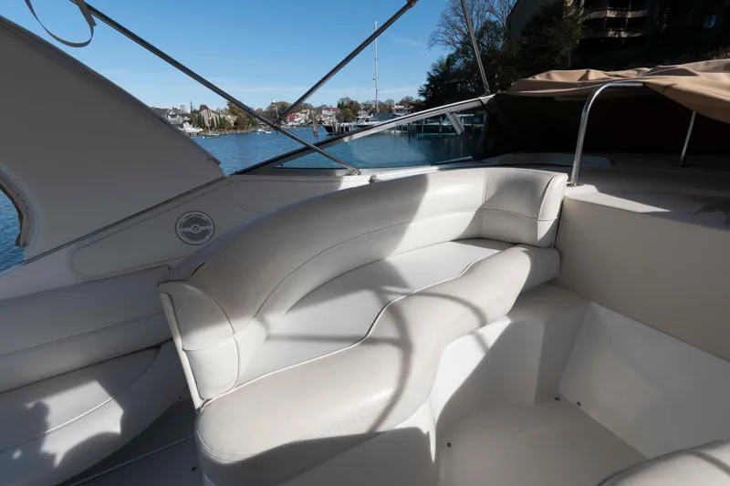 Slide: The Image of 1999 Cruisers Yachts 3575 Express interior with white seating, docked by a scenic waterfront. - 8