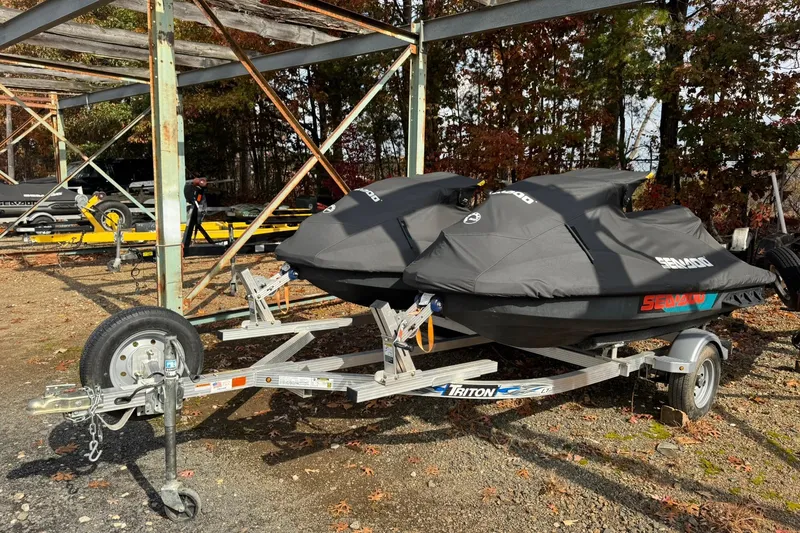 The Image of 2019 Sea-Doo Wake 155 jet skis on a trailer, covered and parked outdoors. - 0