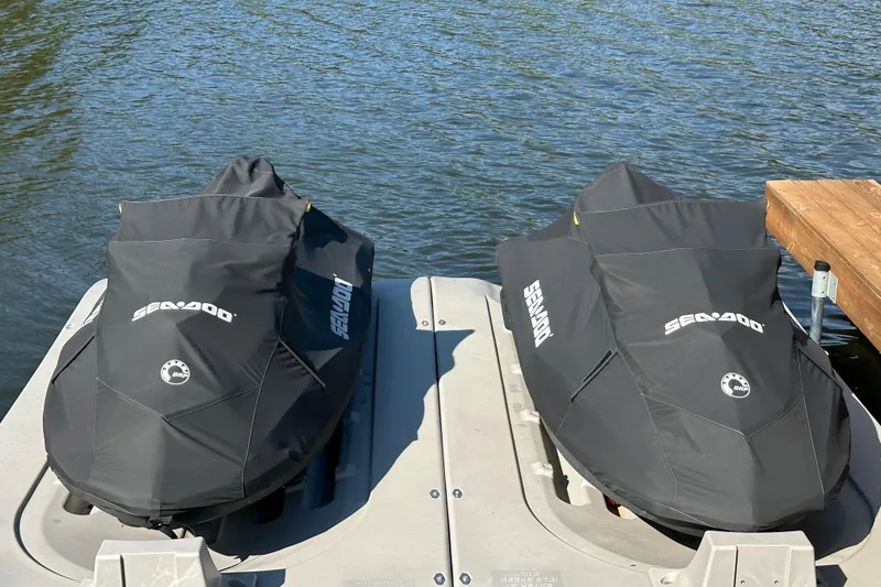 Slide: The Image of Two covered 2019 Sea-Doo Wake 155 jet skis docked by the water. - 3