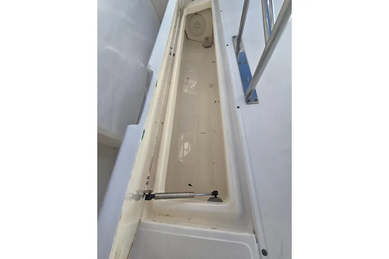 Slide: The Image of 2004 Boston Whaler 270 Outrage storage compartment, open and empty, with metal railing. - 21