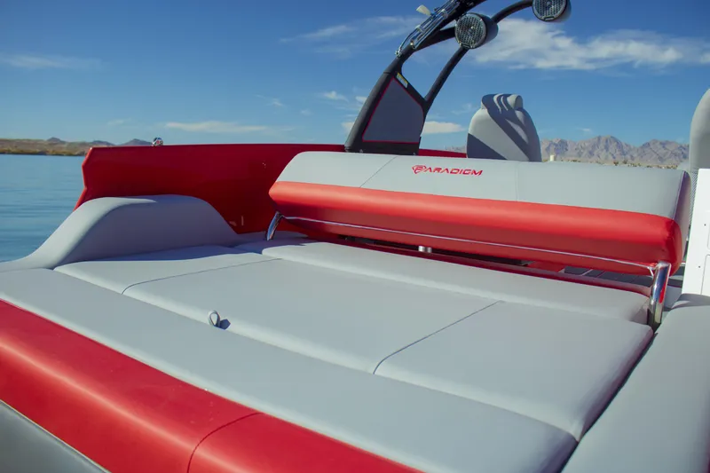 Slide: The Image of 2024 Paradigm Damascus 296 Surf boat interior with red and gray seating, on a serene lake. - 11