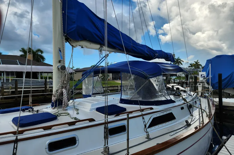 Slide: The Image of 1990 Catalina/Morgan 44 Center Cockpit sailboat docked, featuring blue canvas covers and clear skies. - 15
