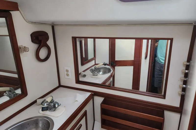 Slide: The Image of 1990 Catalina/Morgan 44 Center Cockpit bathroom with sink, mirror, and wooden accents. - 17