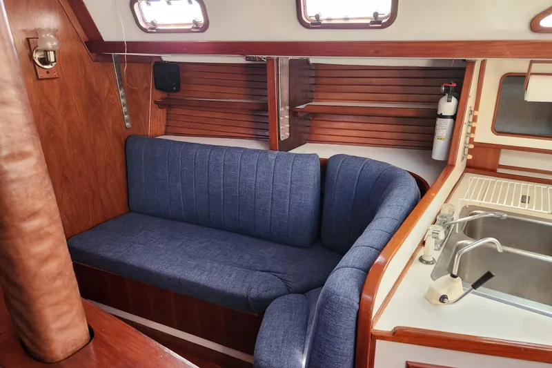 Slide: The Image of Interior of 1990 Morgan 44 Center Cockpit yacht with blue seating and wooden accents. - 8