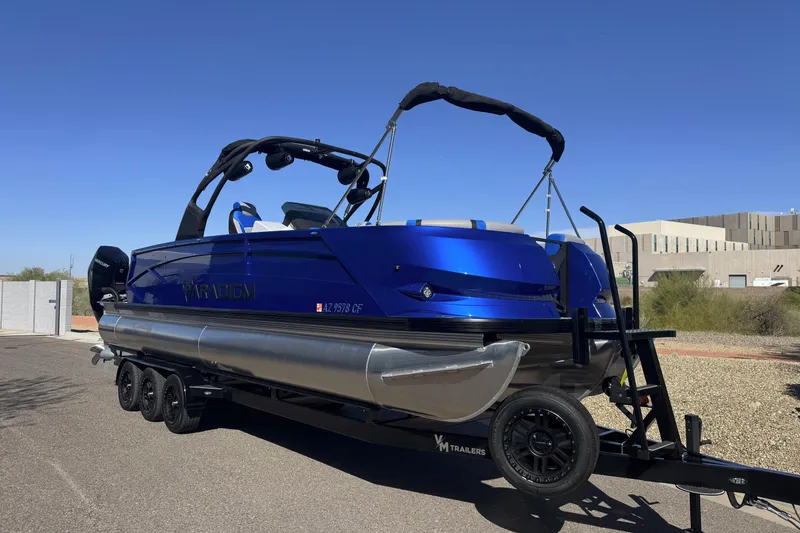 The Image of 2025 Paradigm 27SST pontoon boat on trailer, vibrant blue finish, sunny day. - 0