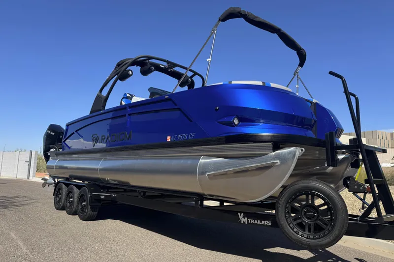 Slide: The Image of 2025 Paradigm 27SST pontoon boat on trailer, vibrant blue finish, sunny day. - 12