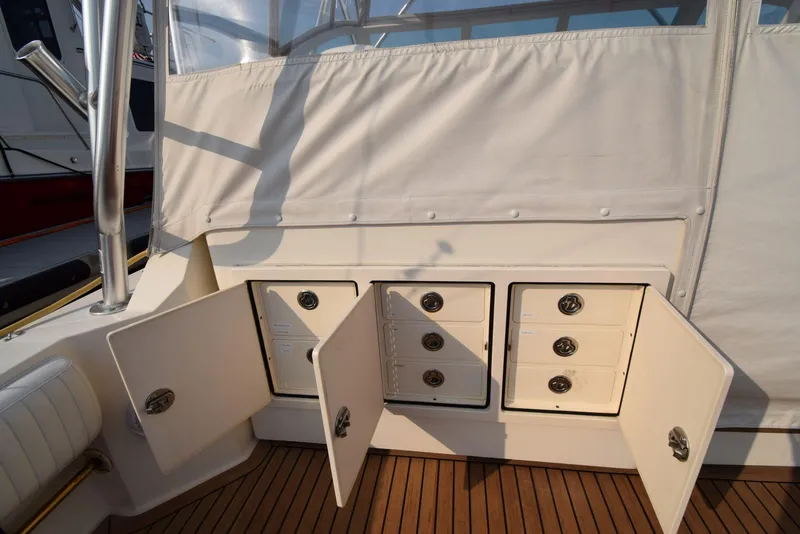 Slide: The Image of 2007 Carolina Classic 28 Express boat storage compartments with open doors on teak deck. - 16