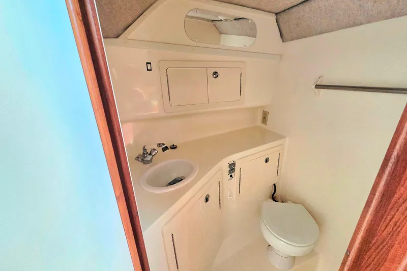 Slide: The Image of 2007 Carolina Classic 28 Express boat bathroom with sink, toilet, and storage cabinets. - 19