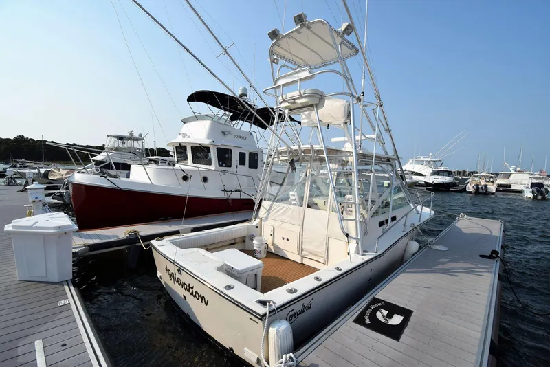 Slide: The Image of 2007 Carolina Classic 28 Express boat docked at marina, featuring a spacious deck and tower. - 6