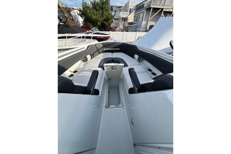 Slide: The Image of 2021 Crownline 265 SS boat interior with seating and storage, docked near houses. - 11