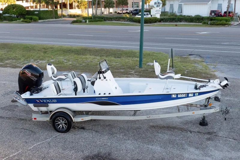 Slide: The Image of 2020 Vexus AVX1980CC boat on trailer, parked roadside, featuring sleek design and modern outboard motor. - 18