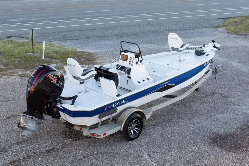 Slide: The Image of 2020 Vexus AVX1980CC boat on trailer, parked near road with buildings in background. - 2