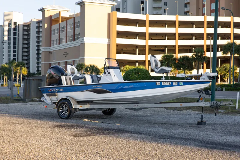 Slide: The Image of 2020 Vexus AVX1980CC boat on trailer, parked near modern buildings. - 4