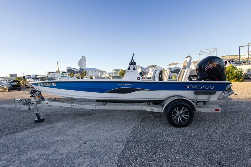 Slide: The Image of 2020 Vexus AVX1980CC boat on trailer, blue and white design, parked outdoors. - 5