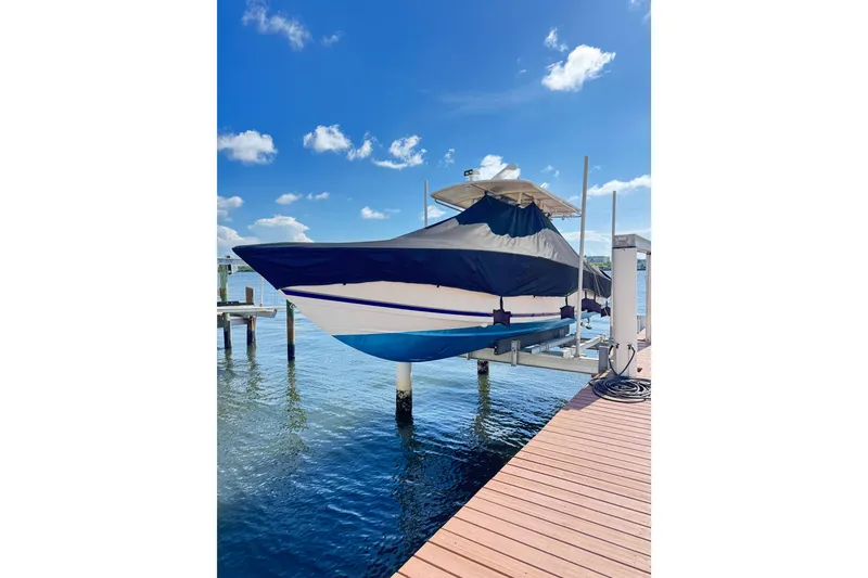 Slide: The Image of 2006 Jupiter 31FS boat on lift, covered, with blue sky and water background. - 12