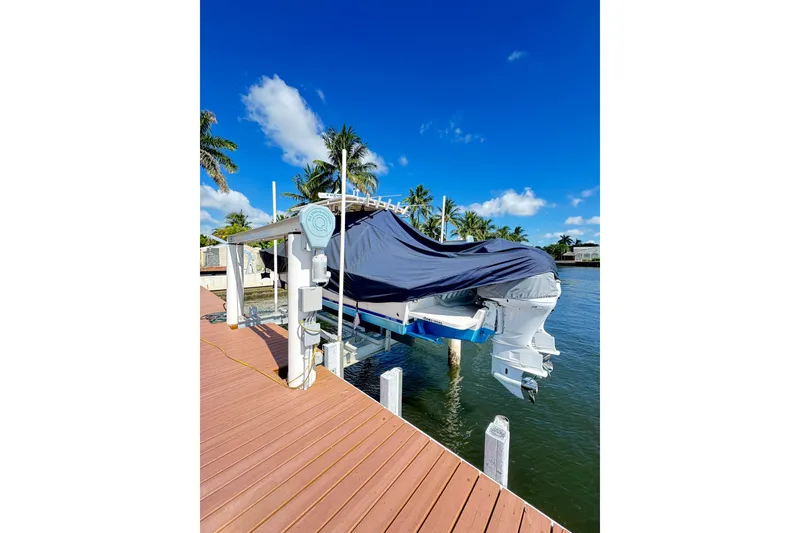 Slide: The Image of Covered 2006 Jupiter 31FS boat on lift by dock, under clear blue sky. - 14