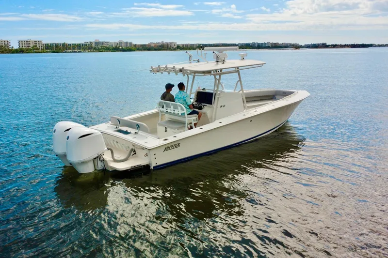 Slide: The Image of 2006 Jupiter 31FS boat on calm water with two people, cityscape in background. - 2