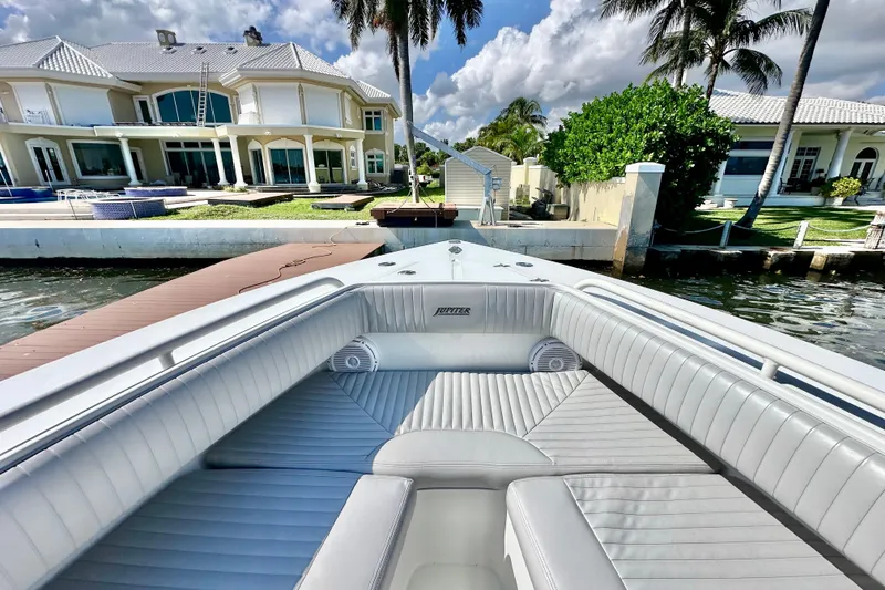 Slide: The Image of 2006 Jupiter 31FS boat docked near luxurious waterfront homes, under a partly cloudy sky. - 23