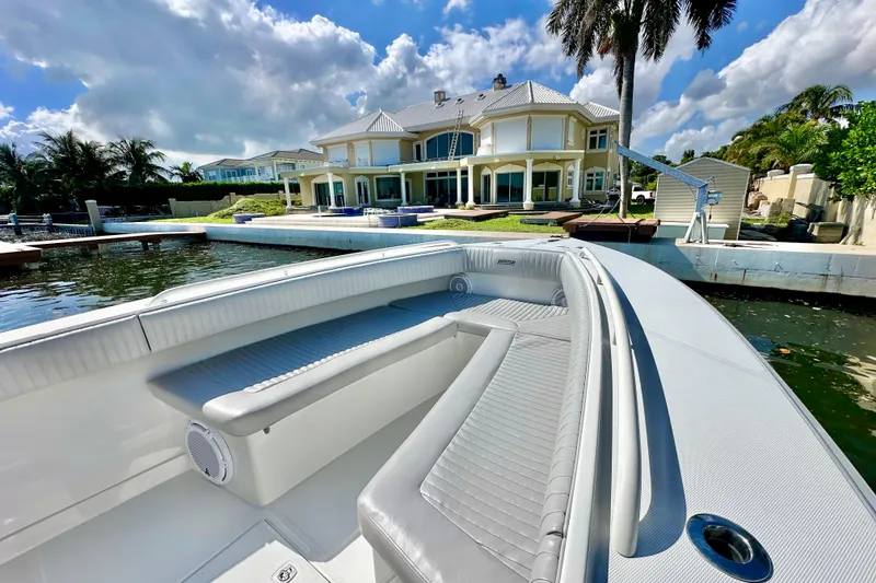 Slide: The Image of 2006 Jupiter 31FS boat docked near luxurious waterfront home under a cloudy sky. - 25