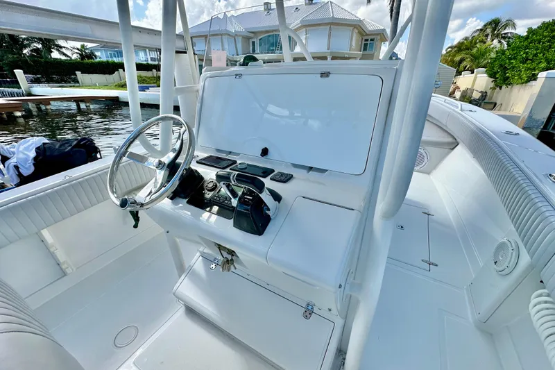 Slide: The Image of 2006 Jupiter 31FS boat helm with steering wheel and controls, docked near waterfront home. - 47