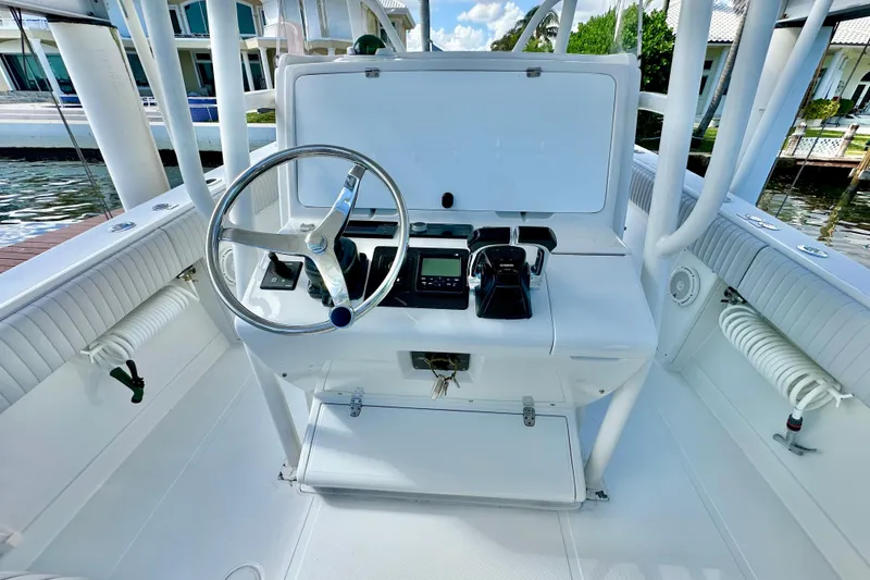 Slide: The Image of 2006 Jupiter 31FS boat helm with steering wheel and controls, docked by waterfront homes. - 48
