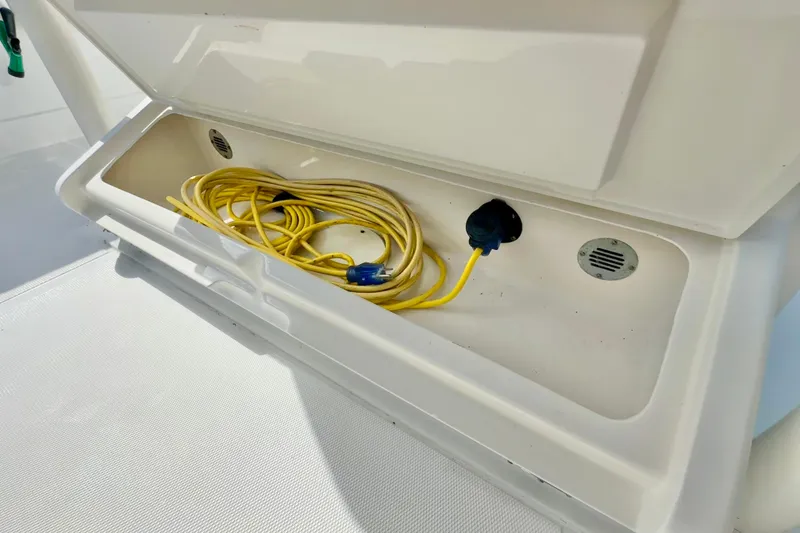 Slide: The Image of Open storage compartment on 2006 Jupiter 31FS boat with yellow power cable. - 52