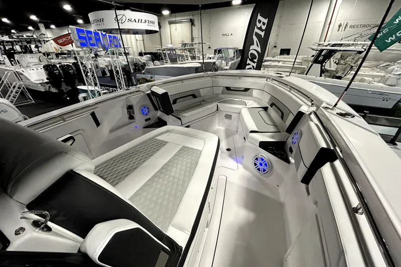 Slide: The Image of 2026 Blackfin 332 CC boat interior at a boat show, featuring sleek seating and modern design. - 11