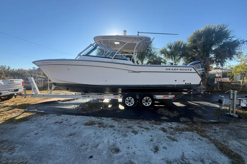 Slide: The Image of 2015 Grady-White Freedom 307 boat on trailer, parked outdoors under clear sky. - 0