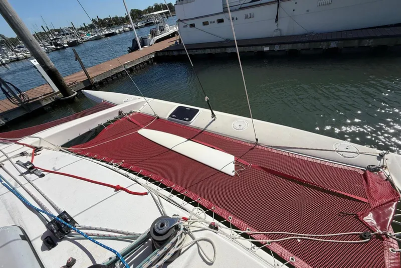 Slide: The Image of 1998 Corsair F-28R #57 sailboat docked at marina, featuring red netting and rigging. - 10