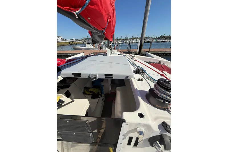 Slide: The Image of 1998 Corsair F-28R #57 sailboat docked, featuring red sails and deck equipment. - 23