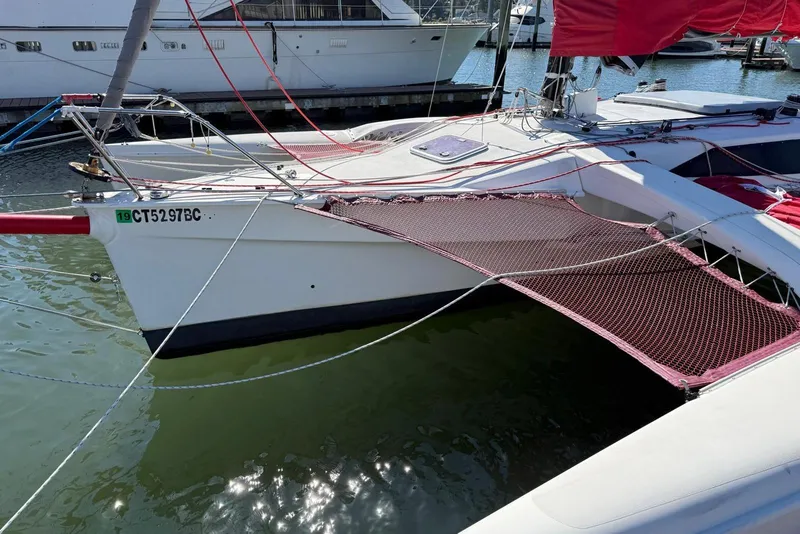 Slide: The Image of 1998 Corsair F-28R #57 trimaran docked with red netting and sails. - 6