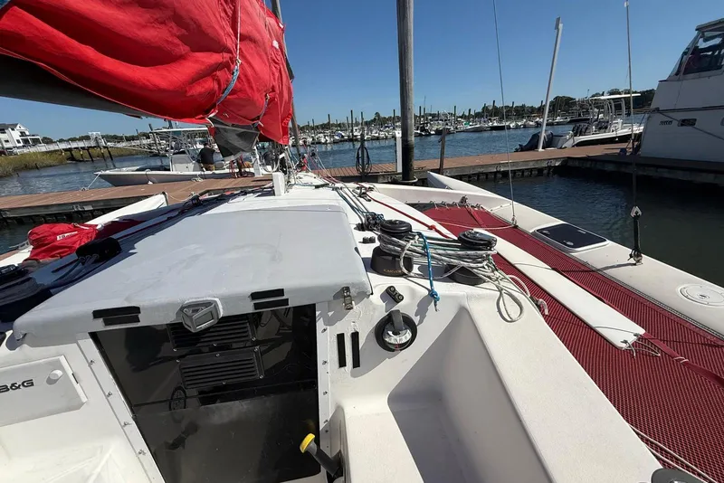 Slide: The Image of 1998 Corsair F-28R #57 sailboat docked, featuring red sails and marina background. - 7