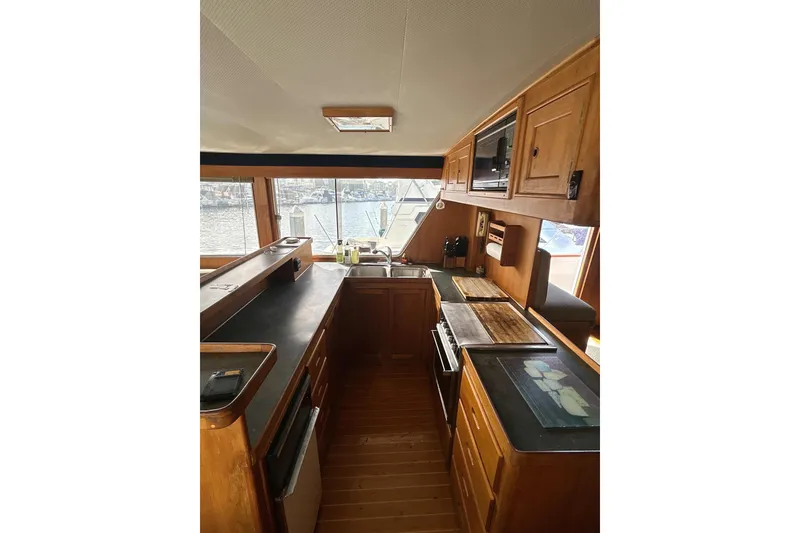 Slide: The Image of 1985 Kong & Halvorsen Island Gypsy yacht kitchen with wooden cabinetry and waterfront view. - 18