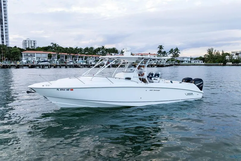 Slide: The Image of 2005 Boston Whaler 320 Outrage Cuddy Cabin on calm water near a marina. - 11