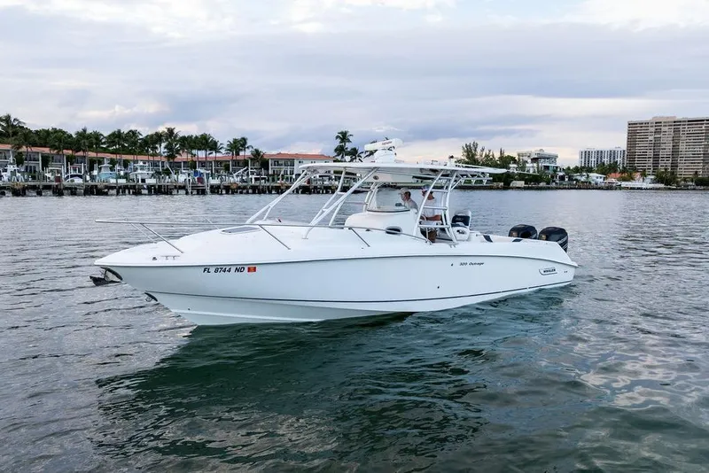 Slide: The Image of 2005 Boston Whaler 320 Outrage Cuddy Cabin on calm water near waterfront homes. - 13