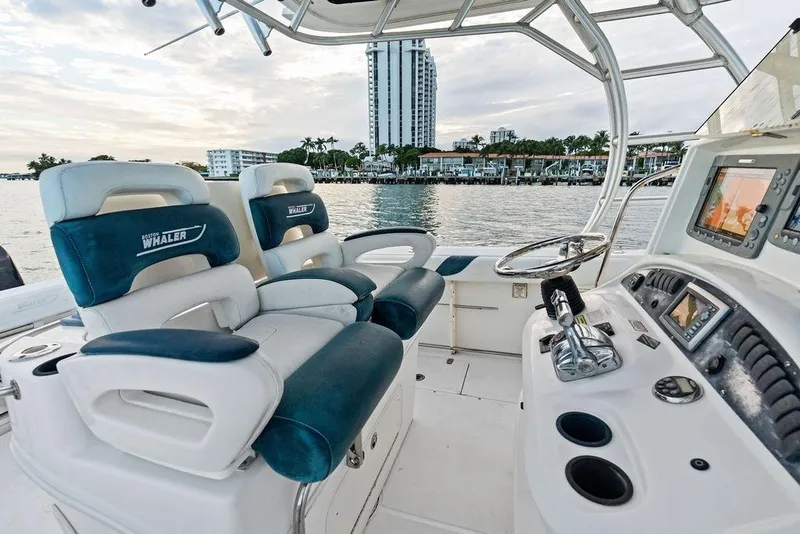 Slide: The Image of 2005 Boston Whaler 320 Outrage Cuddy Cabin interior with helm and seating, waterfront view. - 27