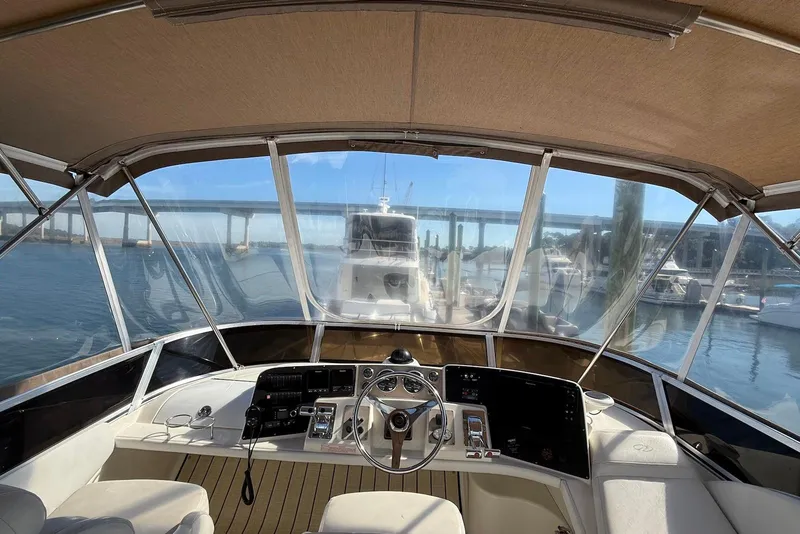 Slide: The Image of 2003 Regal Commodore 3880 yacht cockpit with steering wheel, dashboard, and marina view. - 13