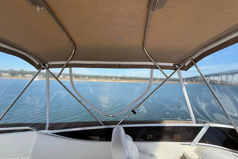 Slide: The Image of 2003 Regal Commodore 3880 boat interior with canopy, overlooking serene water and distant shoreline. - 20