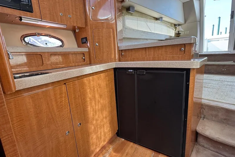 Slide: The Image of Interior of 2003 Regal Commodore 3880 yacht with wooden cabinetry and compact kitchen area. - 31