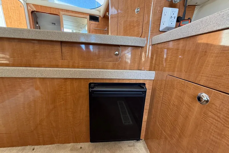 Slide: The Image of 2003 Regal Commodore 3880 yacht interior with wood cabinetry and compact refrigerator. - 32