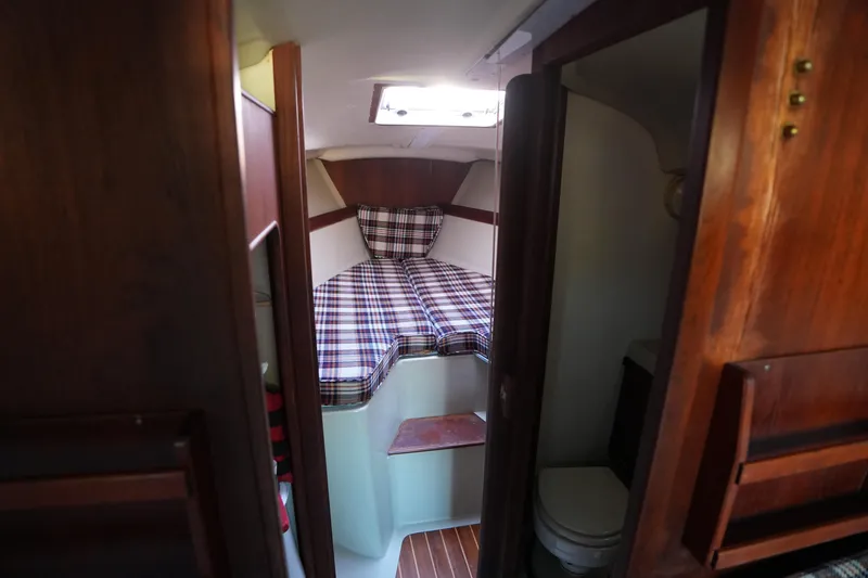 Slide: The Image of Interior of a 1978 C&C 34 sailboat with plaid bedding and wooden finishes. - 11