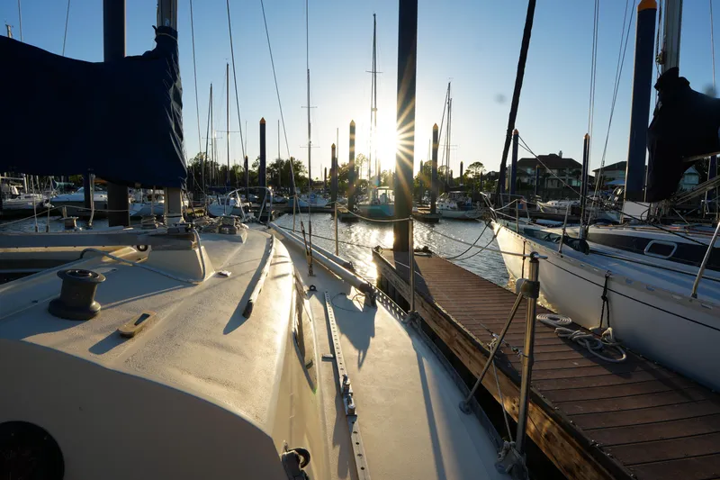 Slide: The Image of 1978 C&C 34 sailboat docked at marina during sunset, surrounded by other boats. - 9