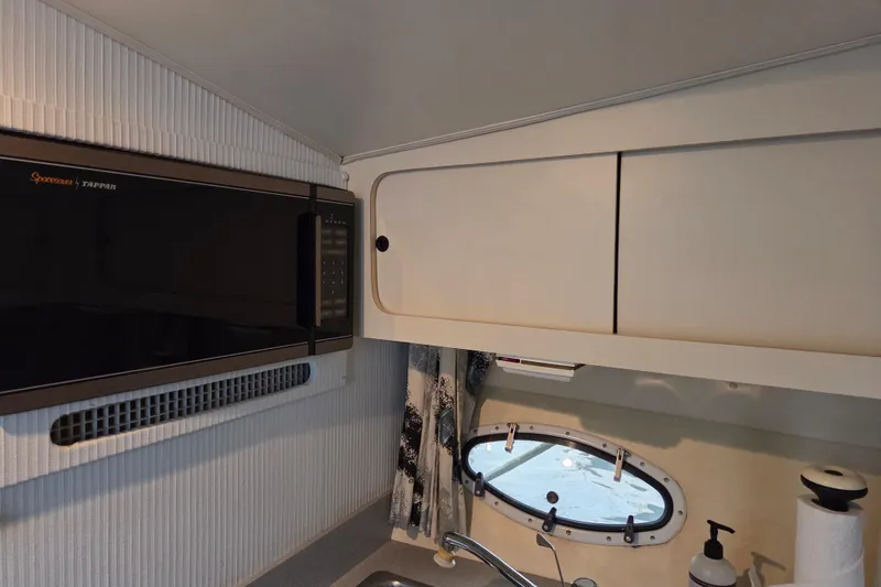 Slide: The Image of 1990 Trojan 10 Meter Express 330 interior with microwave, cabinets, and porthole window. - 30
