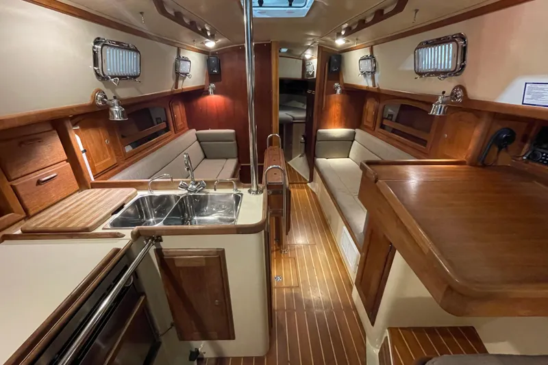 Slide: The Image of Interior of a 1997 Pacific Seacraft 34 sailboat, featuring a cozy wooden cabin and galley. - 18