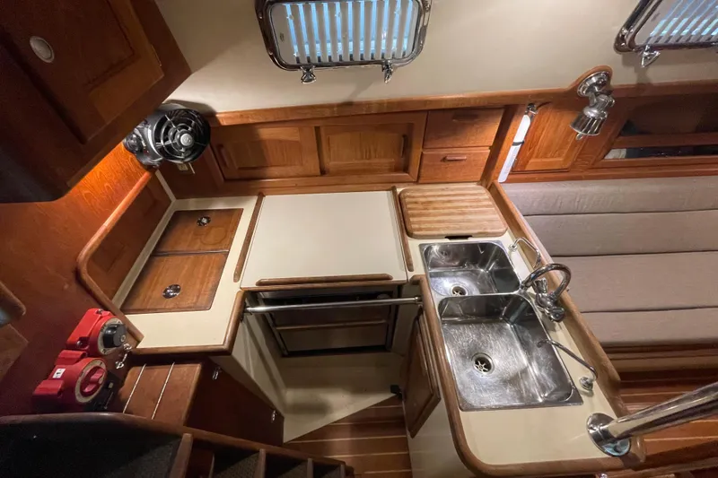 Slide: The Image of Interior of 1997 Pacific Seacraft 34 sailboat, featuring a compact kitchen with wooden cabinetry. - 20