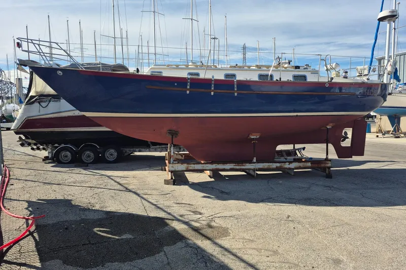 Slide: The Image of 1997 Pacific Seacraft 34 sailboat on dry dock, blue hull, marina background. - 6