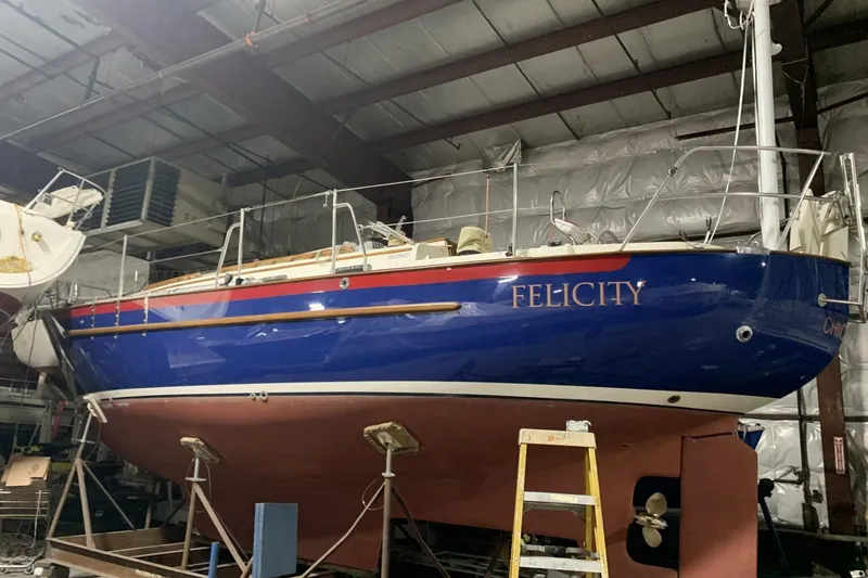 Slide: The Image of 1997 Pacific Seacraft 34 sailboat "Felicity" in indoor storage, blue hull, red stripe. - 7