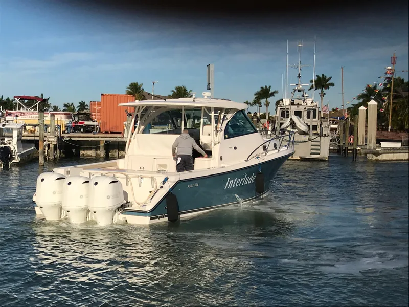 Slide: The Image of 2016 Pursuit OS 385 Offshore boat in marina, clear sky, palm trees in background. - 2